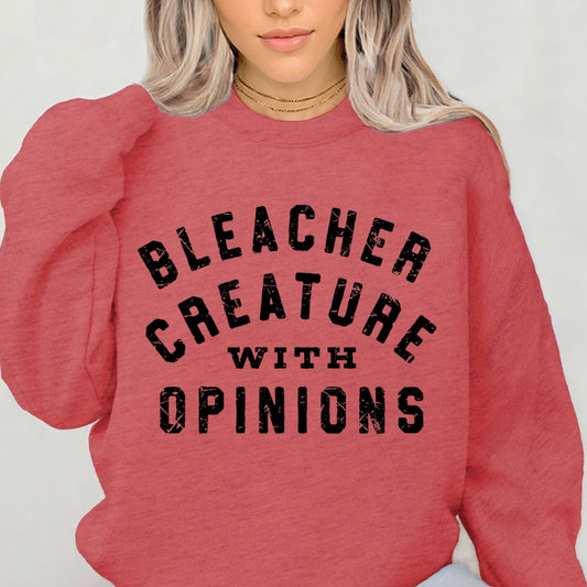 Person wearing a red sweatshirt with 'BLEACHER CREATURE WITH OPINIONS' text on a plain background