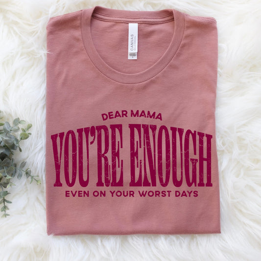 Folded pink t-shirt with text on a white fluffy surface