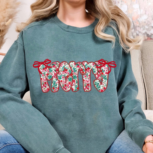 Person wearing a green sweatshirt with floral text design sitting on a couch.