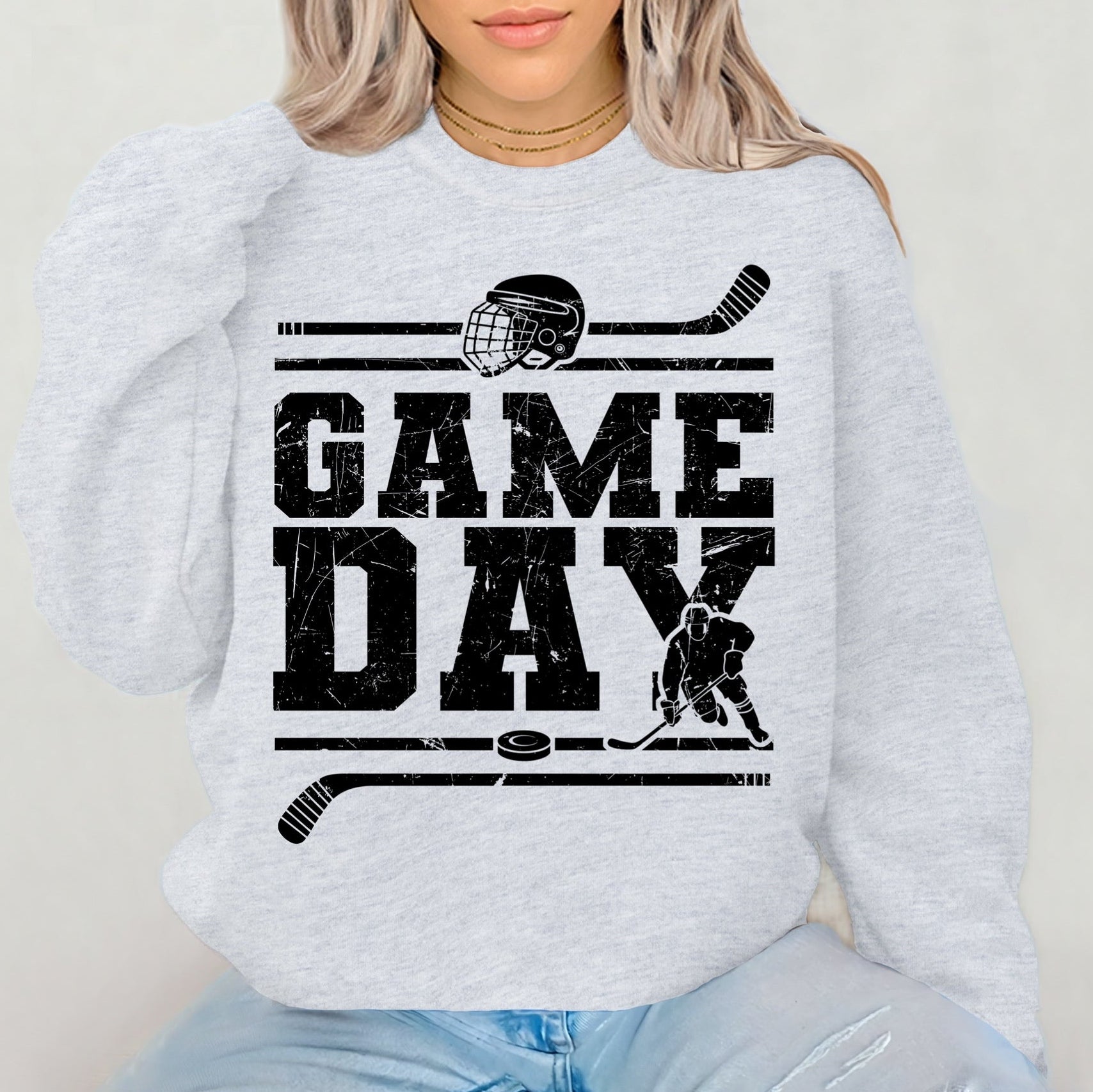 Person wearing a light gray sweatshirt with 'GAMEDAY' and hockey graphics.