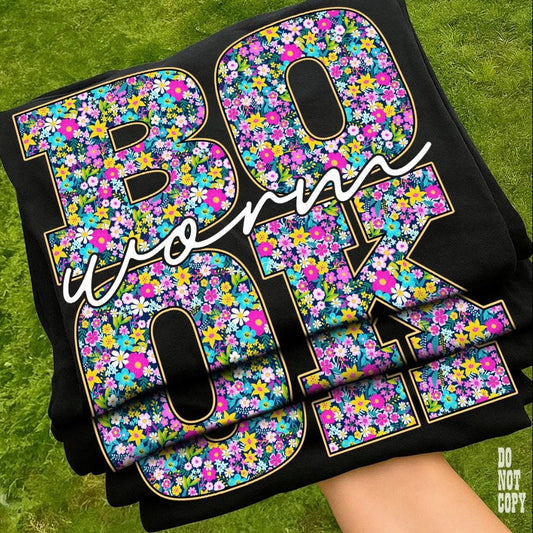 Stack of black towels with floral lettering on a green grass background