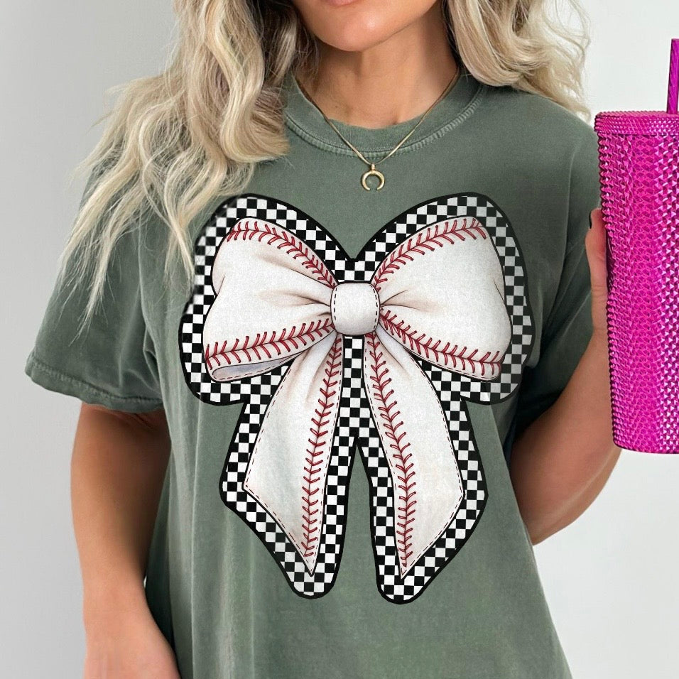 Person wearing a green t-shirt with a large bow design, holding a pink textured tumbler.