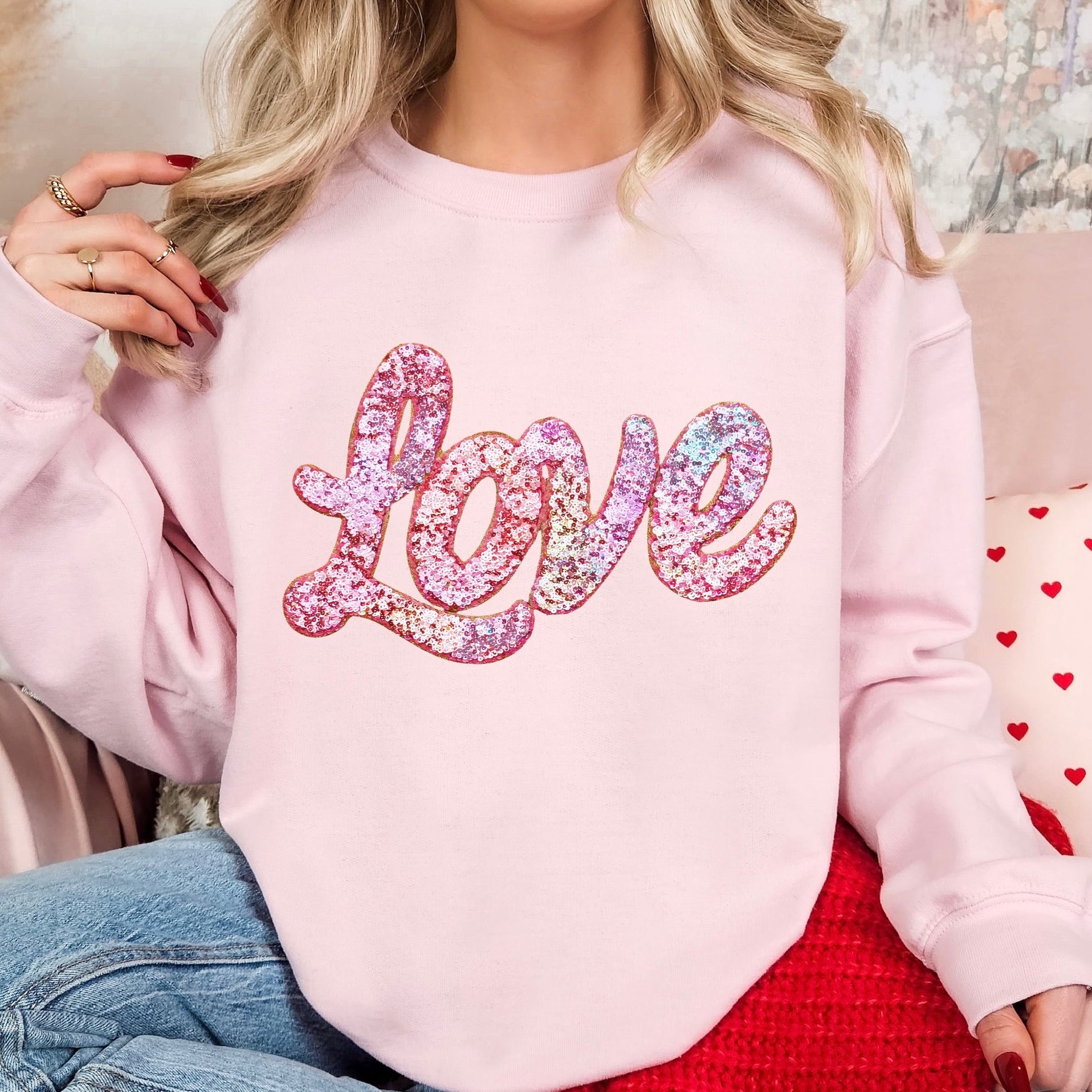 Person wearing a pink sweatshirt with 'love' in colorful letters, sitting on a couch.