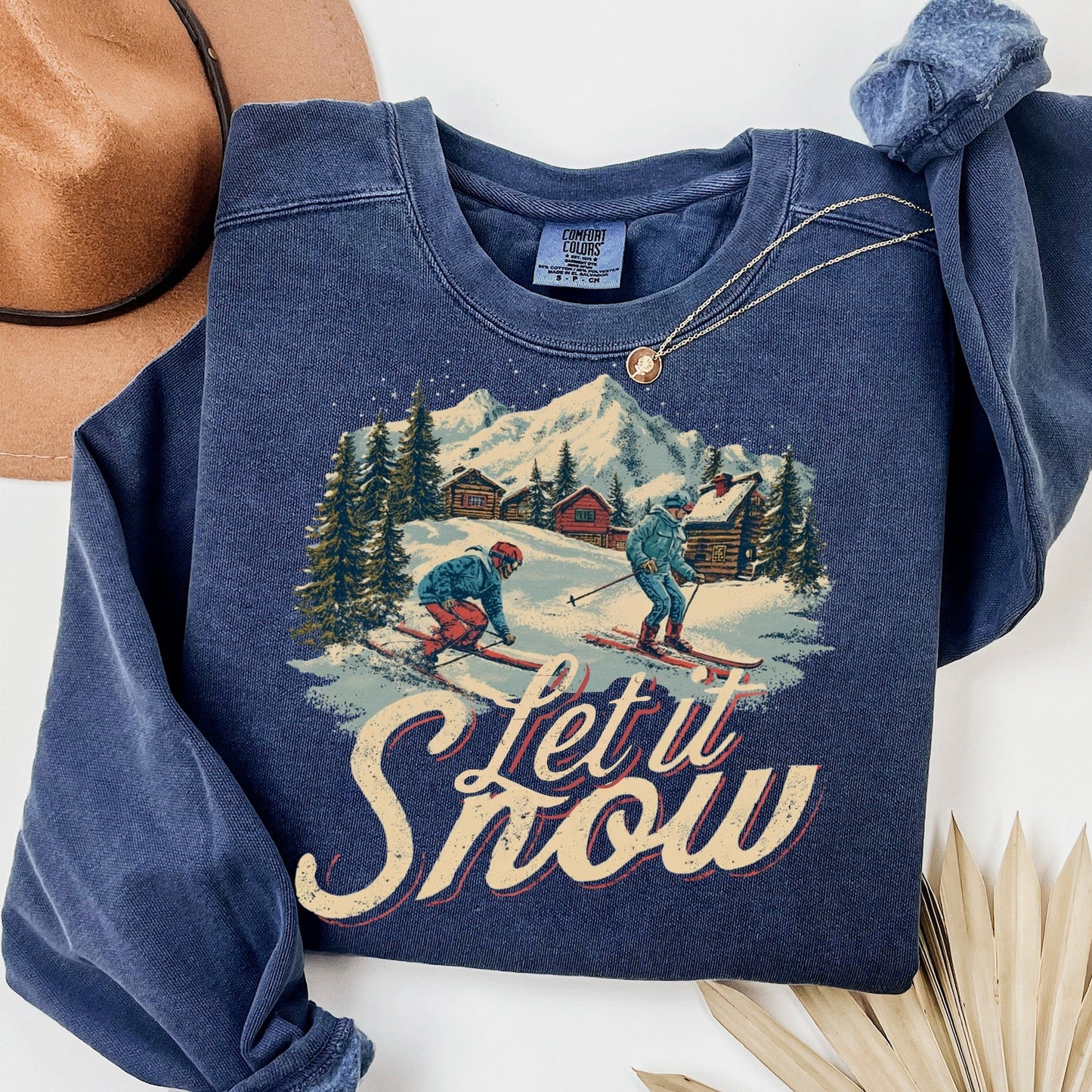 Blue sweatshirt with skiing graphic and 'Let it Snow' text on a white background