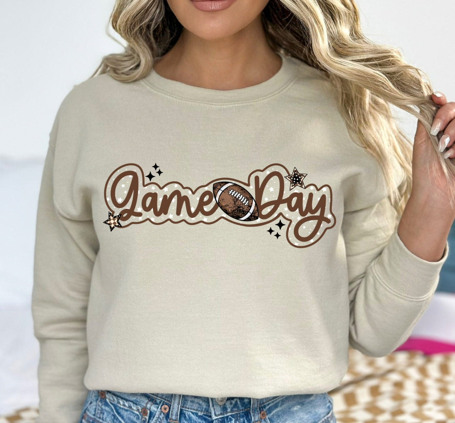 Person wearing a beige sweatshirt with 'Game Day' and football graphic.