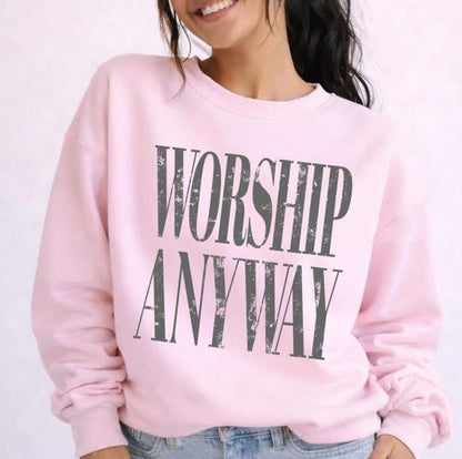 Person wearing a pink sweatshirt with 'Worship Anyway' text on a light background