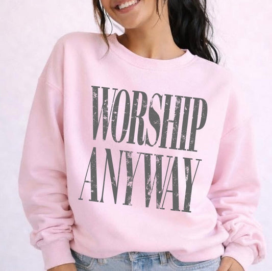 Person wearing a pink sweatshirt with 'Worship Anyway' text on a light background