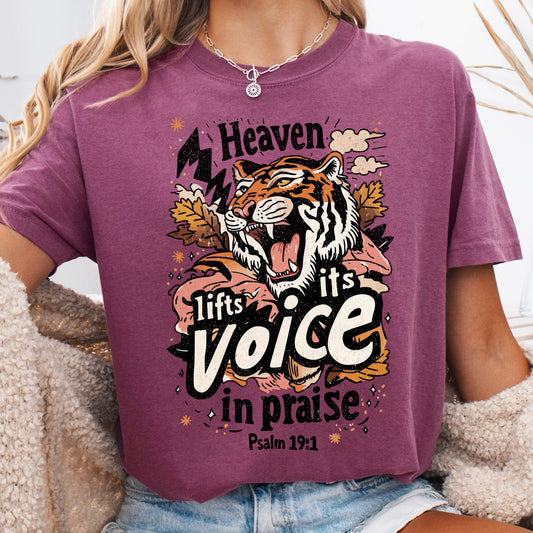 Person wearing a purple t-shirt with a tiger graphic and text, sitting on a fluffy chair.