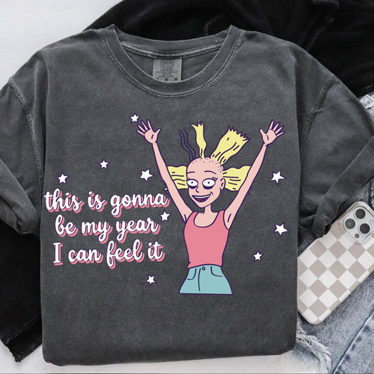Gray sweatshirt with a cartoon character and text 'this is gonna be my year I can feel it' on a white background.