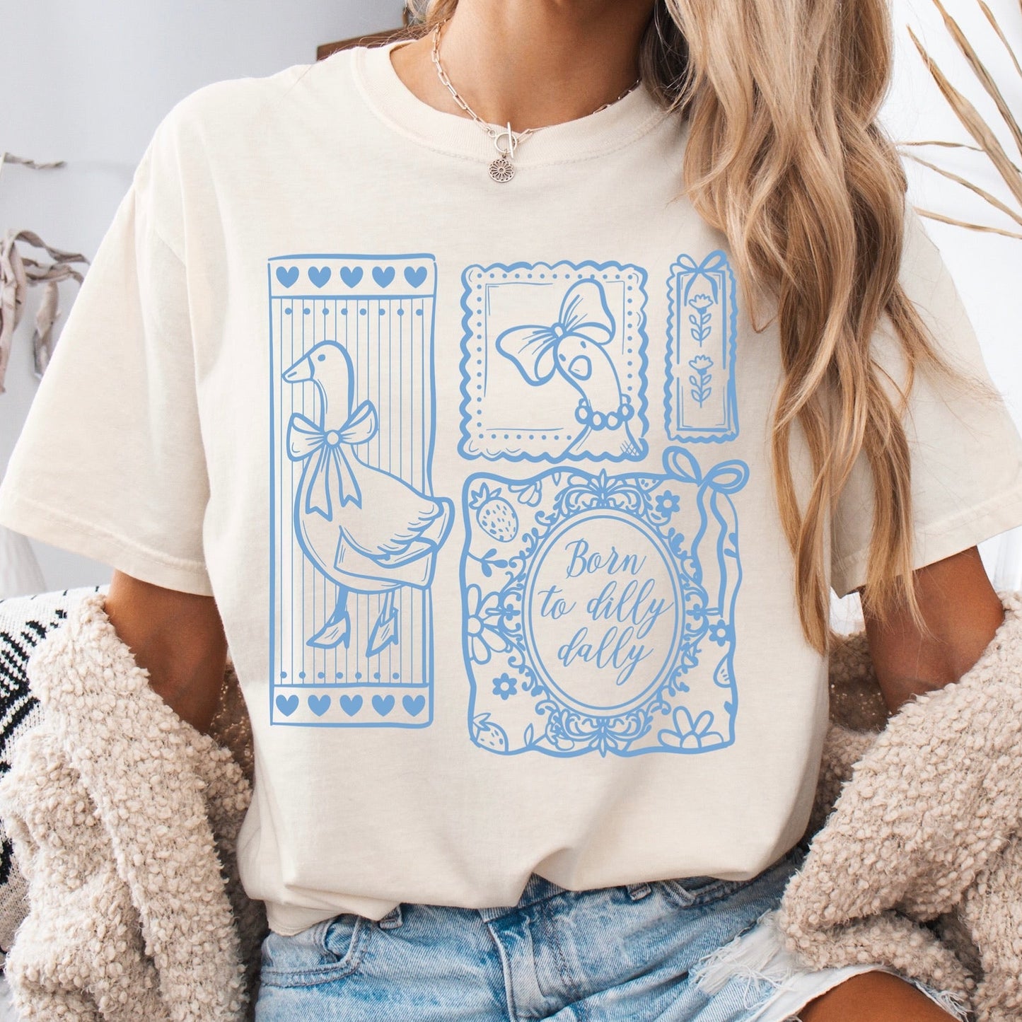 Person wearing a white t-shirt with blue graphic designs and text, sitting indoors.