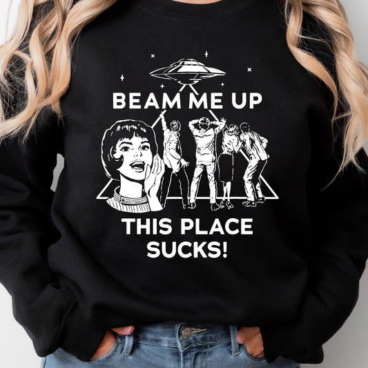 Black sweatshirt with 'Beam Me Up This Place Sucks!' design worn by a person.