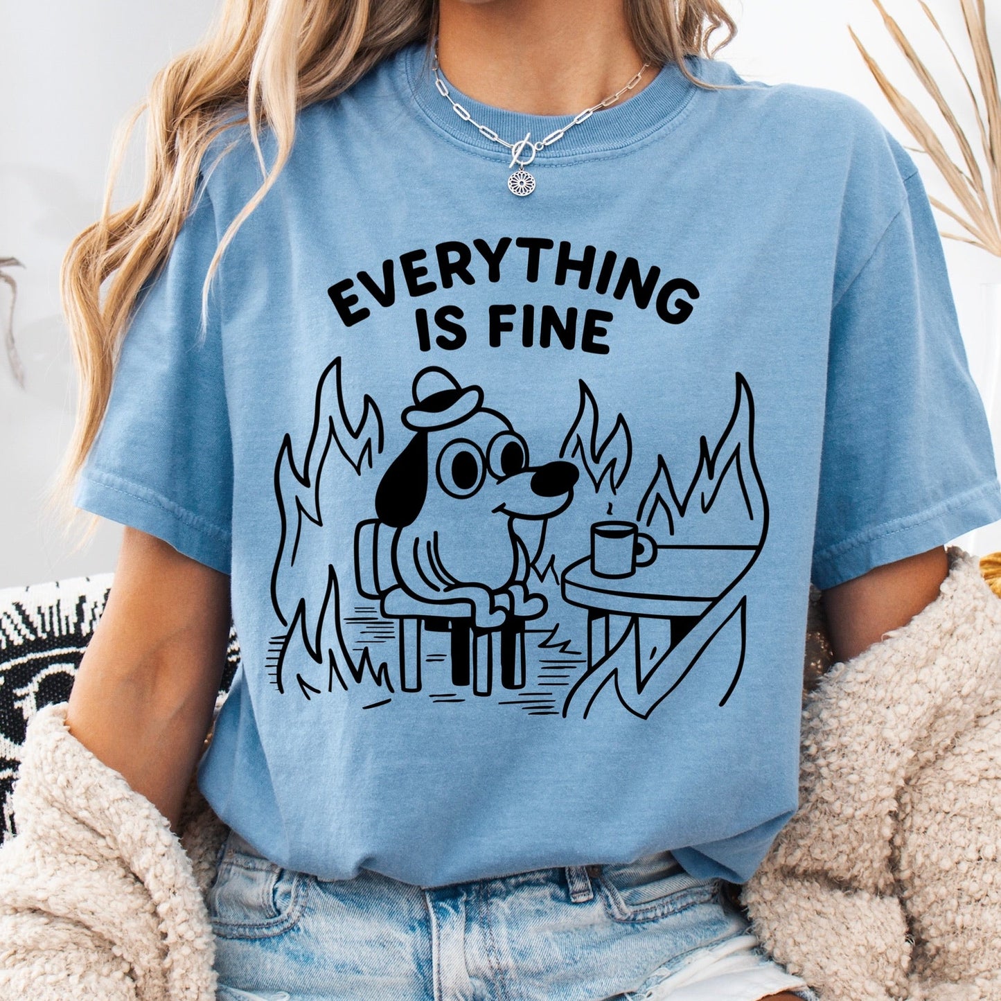 Person wearing a blue t-shirt with a graphic and 'Everything is Fine' text, sitting on a couch.