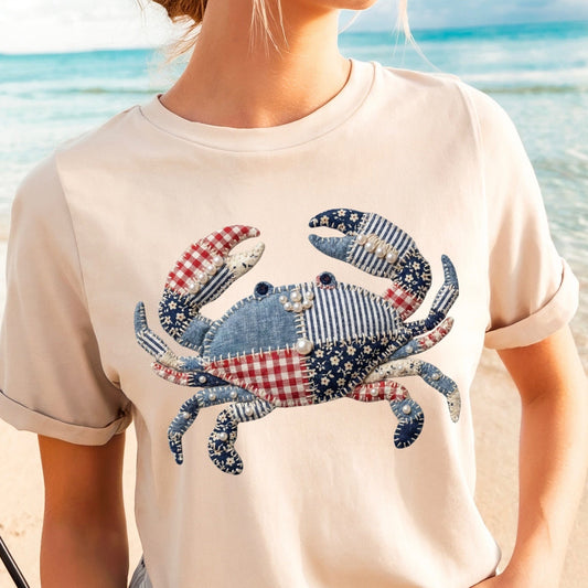 Person wearing a t-shirt with a colorful crab design on a beach.