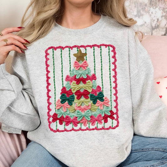 Person wearing a gray sweatshirt with a colorful Christmas tree design made of bows.