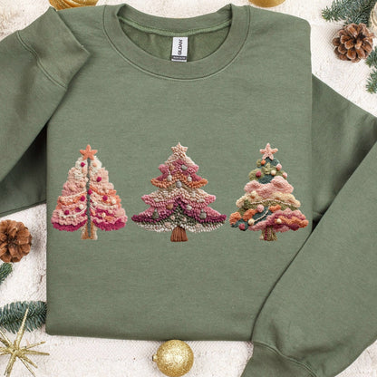 Green sweatshirt with embroidered Christmas tree design on a decorative background with ornaments and pine branches.
