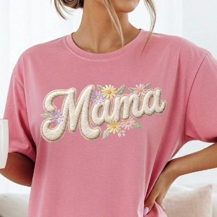 Pink t-shirt with 'Mama' and floral design worn by a person, holding a mug with a heart design.