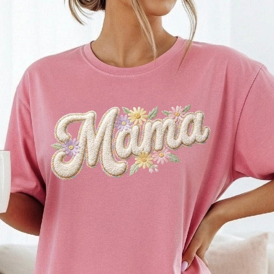 Pink t-shirt with 'Mama' and floral design worn by a person, holding a mug with a heart design.