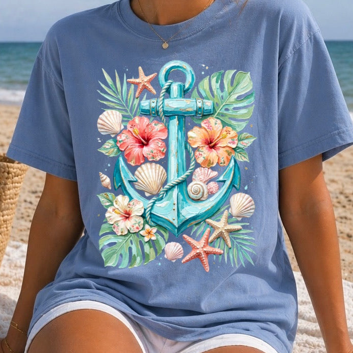 Woman wearing a blue t-shirt with a colorful anchor design on a beach.