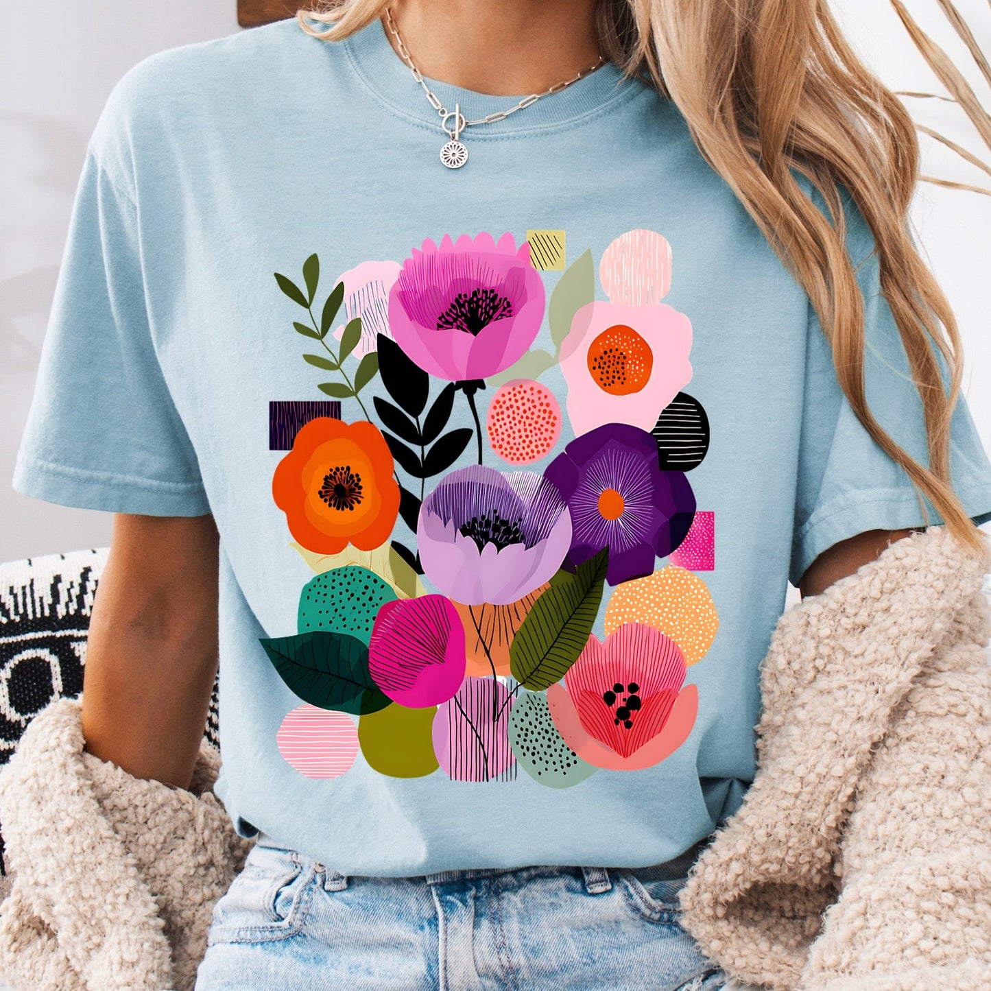 Person wearing a light blue t-shirt with colorful floral design, sitting on a couch.