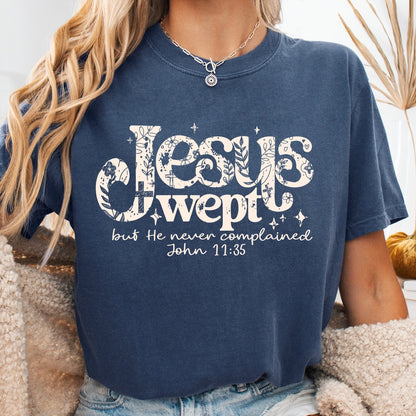 Person wearing a navy blue t-shirt with 'Jesus wept' text, sitting on a couch.