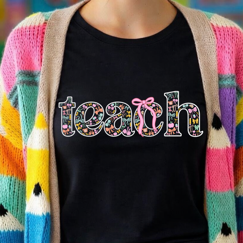 Person wearing a colorful cardigan over a black shirt with 'teach' text in a classroom setting