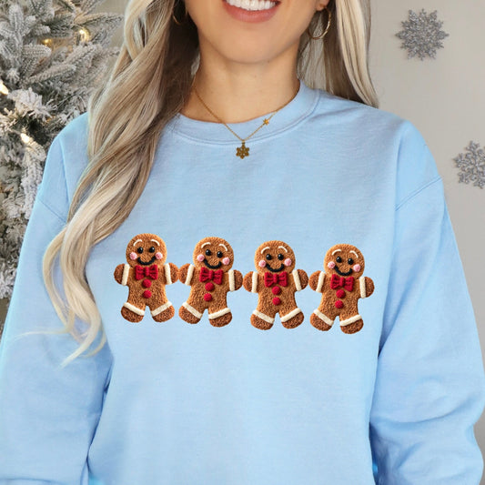 Person wearing a light blue sweatshirt with gingerbread man design in front of a Christmas tree.
