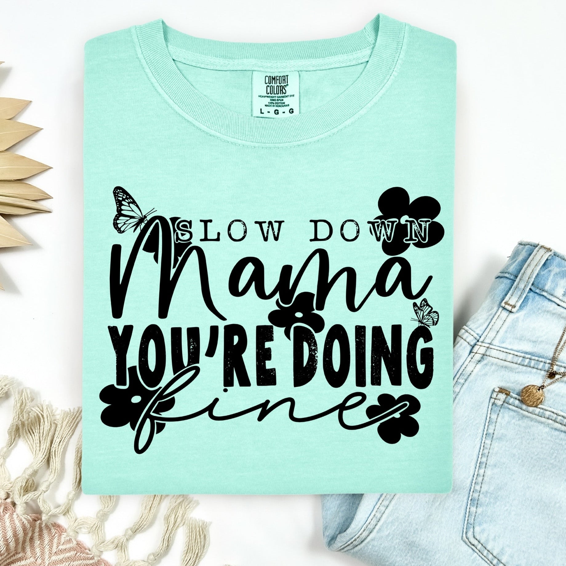 Mint green t-shirt with black text and butterfly graphics on a white background