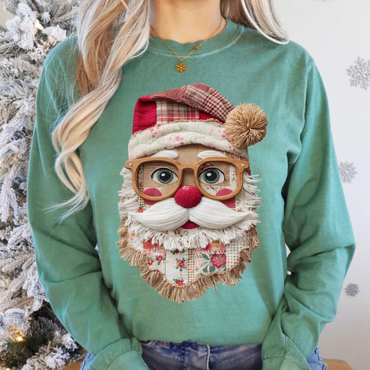 Person wearing a green sweater with a Santa Claus design, sitting in front of a decorated Christmas tree.