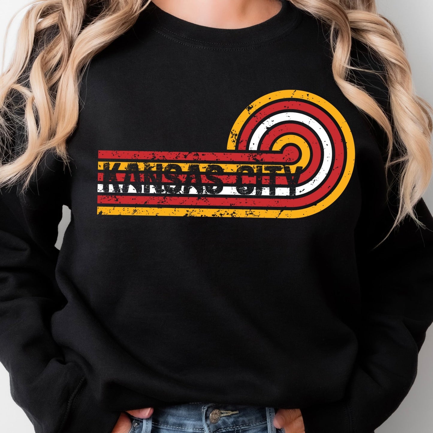 Person wearing a black sweatshirt with a colorful 'Kansas City' design on a plain background