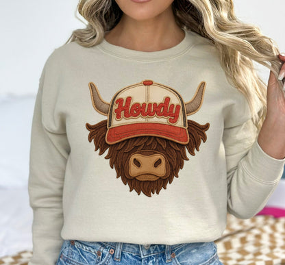 Person wearing a beige sweatshirt with a cow graphic and 'Howdy' text, standing outdoors.