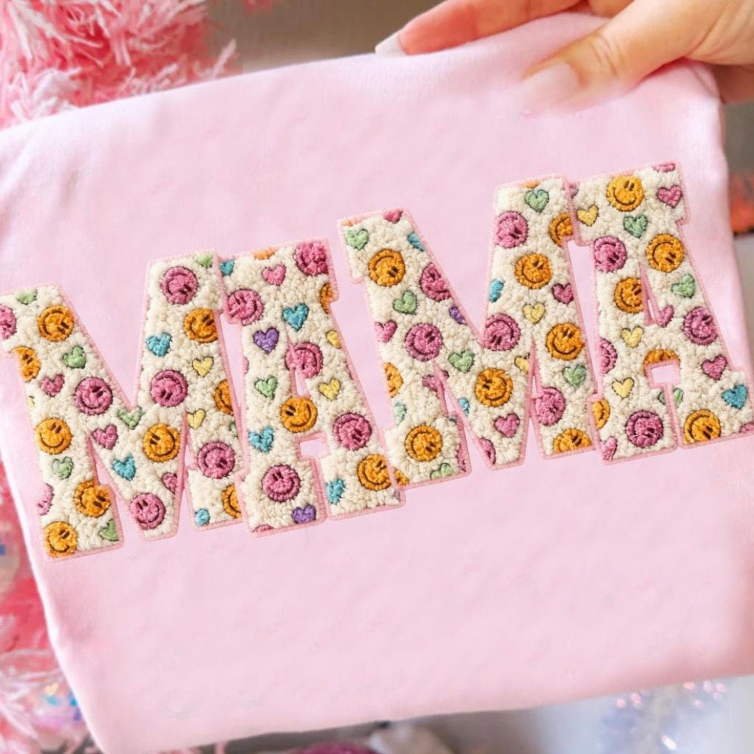 Pink fabric with 'Mum' embroidered in floral letters held by a hand.