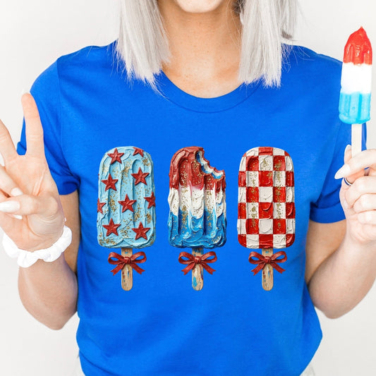 Person wearing a blue t-shirt with ice cream cone design, holding a colorful popsicle against a white background.