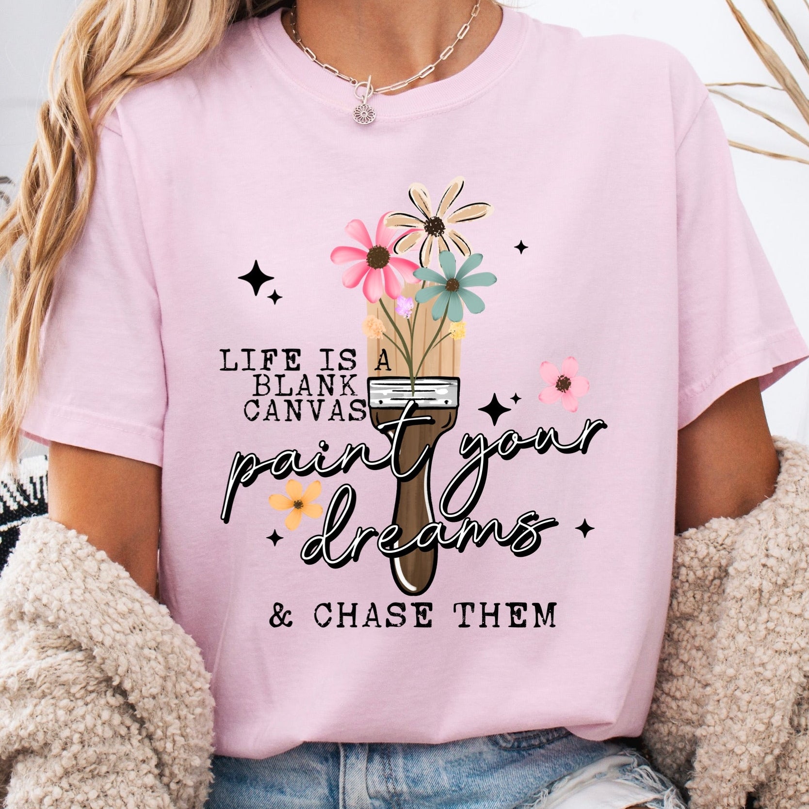 Person wearing a pink t-shirt with a motivational quote and graphic design.