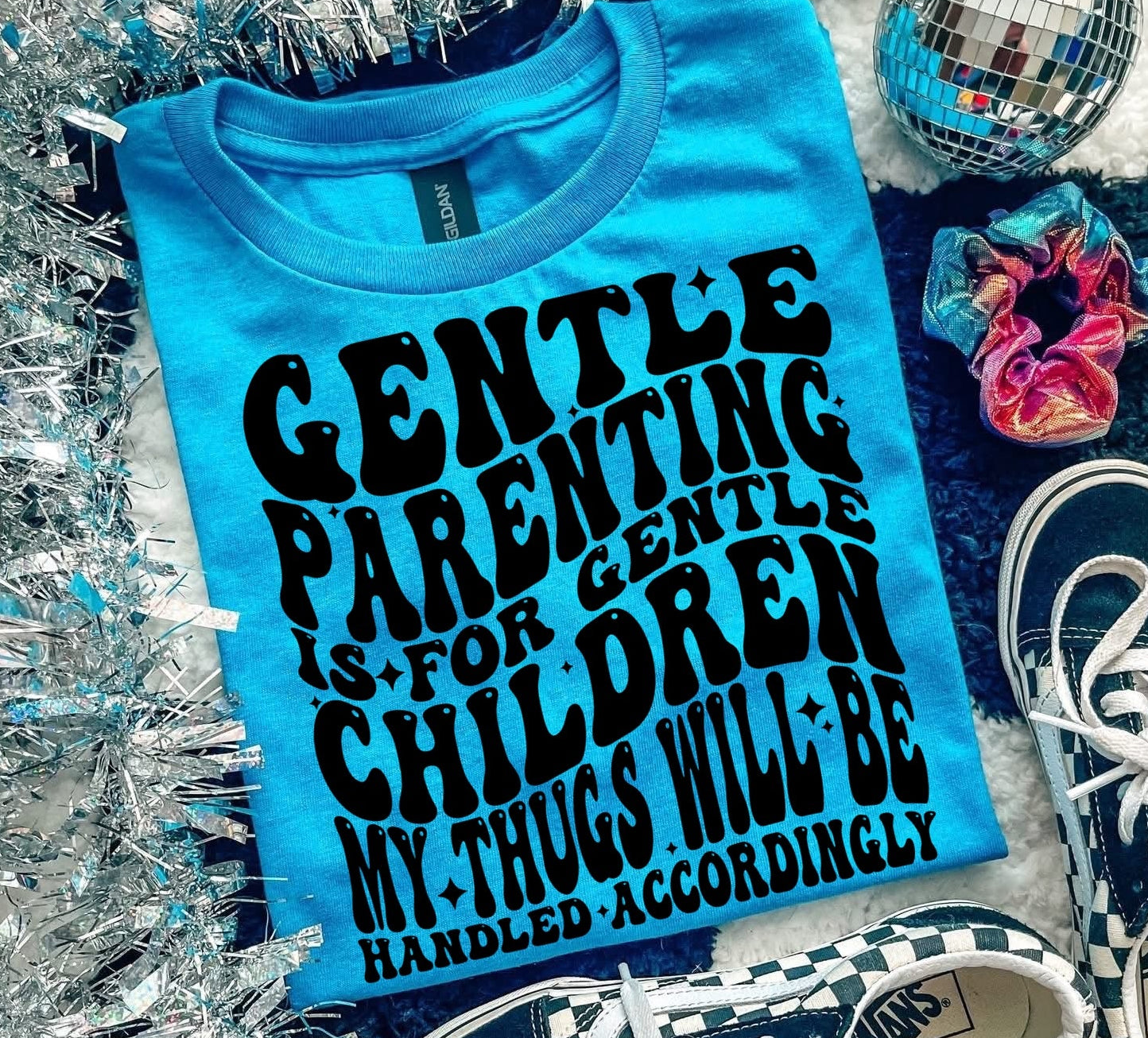 Blue t-shirt with humorous text, checkered sneakers, and decorative items on a textured surface.