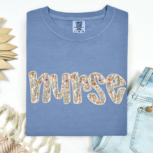 Blue t-shirt with 'NURSE' in floral letters on a white background