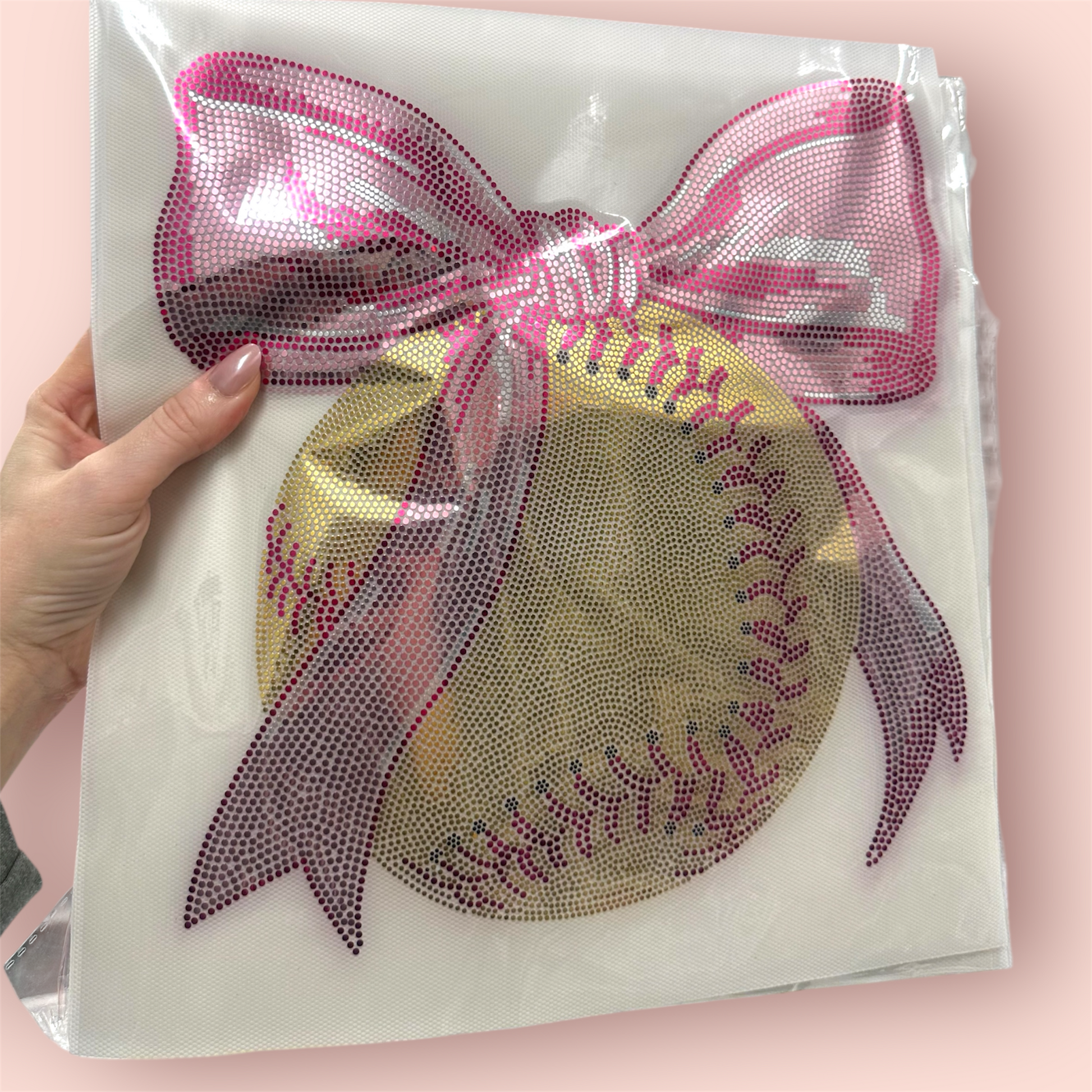 Decorative patch with a softball design and pink bow on a clear background