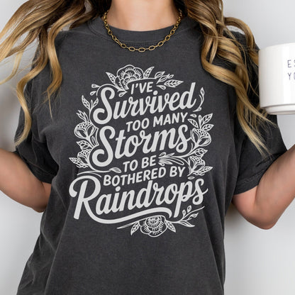 Person wearing a black t-shirt with a motivational quote, holding a white mug.survived too many storms screen print transfer