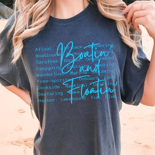 Person wearing a dark blue t-shirt with blue text on a beach.