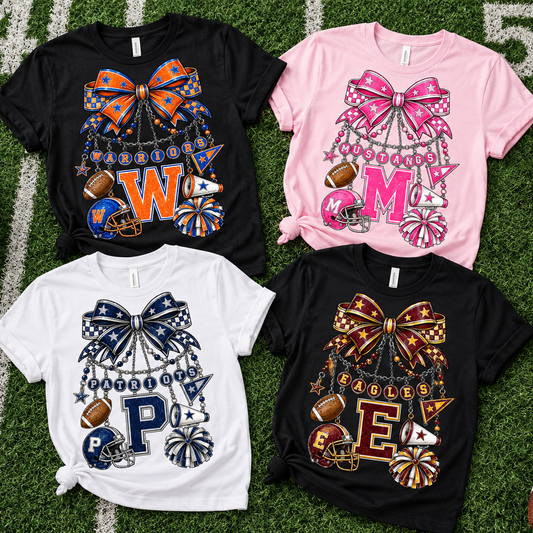 Four short-sleeve graphic T-shirts laid flat on a football-field background with sports props. The shirts are black, pink, and white, each featuring a large decorative bow and cheerleader-themed graphic with monogram letters and football motifs.